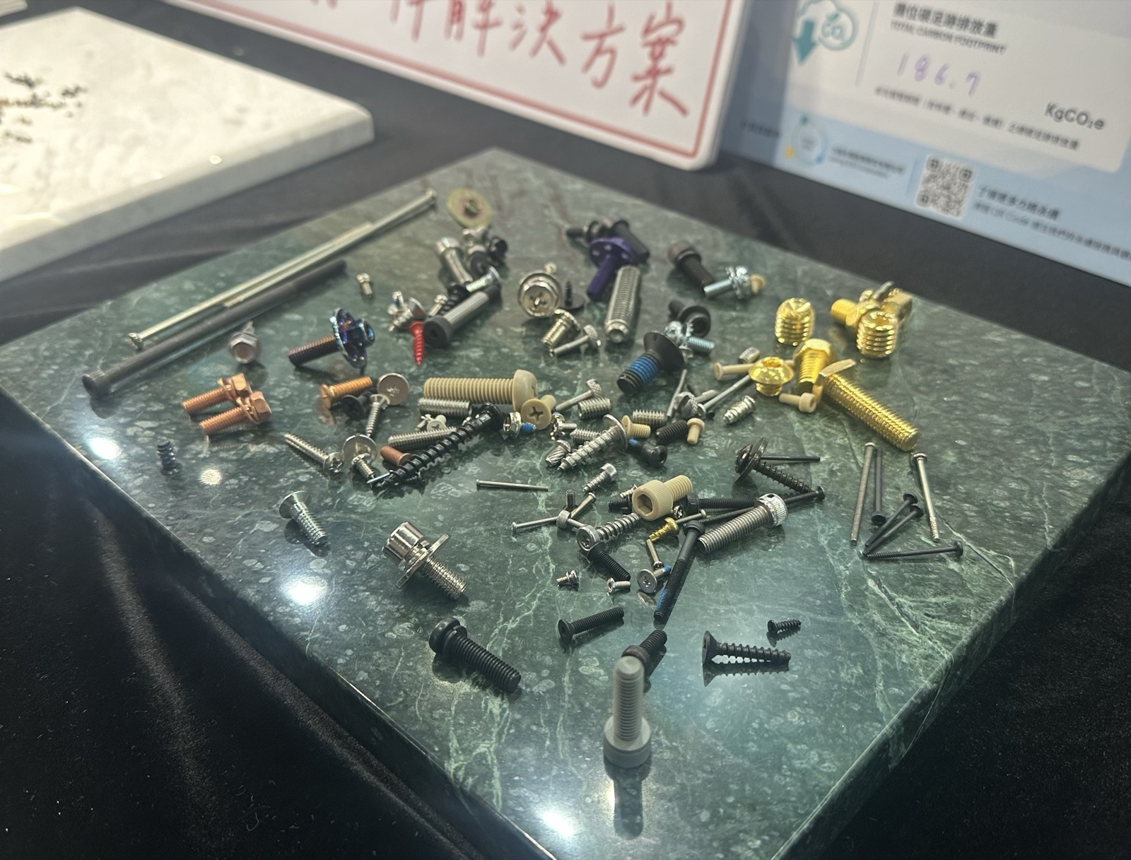 攤在大理石板上的各式扣件：不同頭型、驅動型式、表面處理與直徑